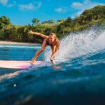 Bali Tour Beautiful surfer girl on surfboard. Woman in ocean during surfing in Bali