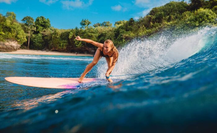 Bali Tour Beautiful surfer girl on surfboard. Woman in ocean during surfing in Bali